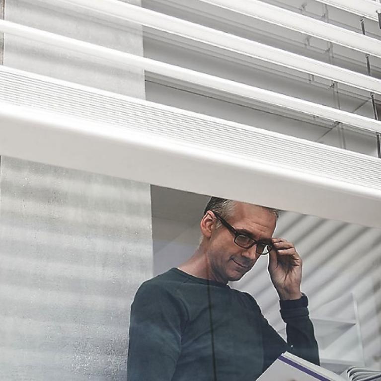 ROMA External Venetian Blinds in White Man reads book behind window, detailed view, external venetian blinds, open